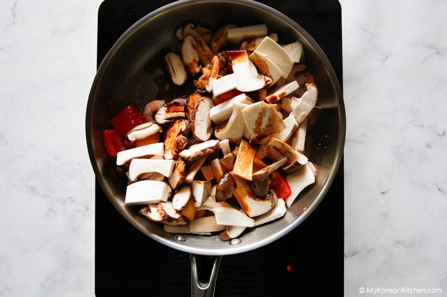 Lanjutkan menggoreng jamur dan bahan lainnya dalam wajan setelah menambahkan saus.