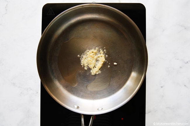Bawang putih cincang berwarna kecokelatan dalam panci stainless steel.