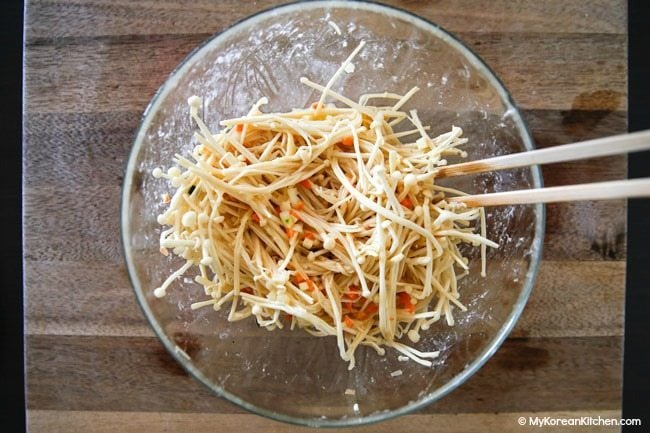 Mixing enoki mushrooms with egg and vegetable mixture
