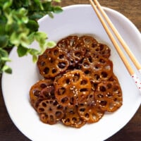braised lotus root in an oval-shaped bowl with chopsticks resting on top