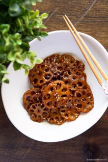 braised lotus root in an oval-shaped bowl with chopsticks resting on top
