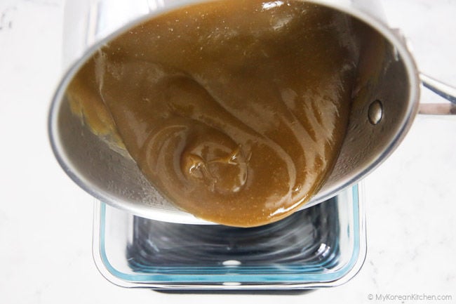 Transferring acorn jelly to a glass container to set its shape.