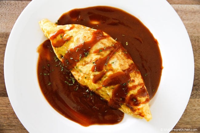 Football shaped omurice served on a white plate with brown sauce