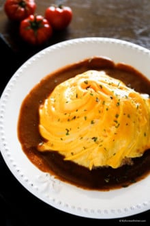 Omurice on a white plate with brown sauce