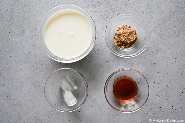 Ingredients for misugaru latte including milk, misugaru powder, ice cubes, and honey.