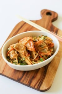 Sweet and spicy Korean dumpling salad (bibim mandu) served in a white oval bowl.