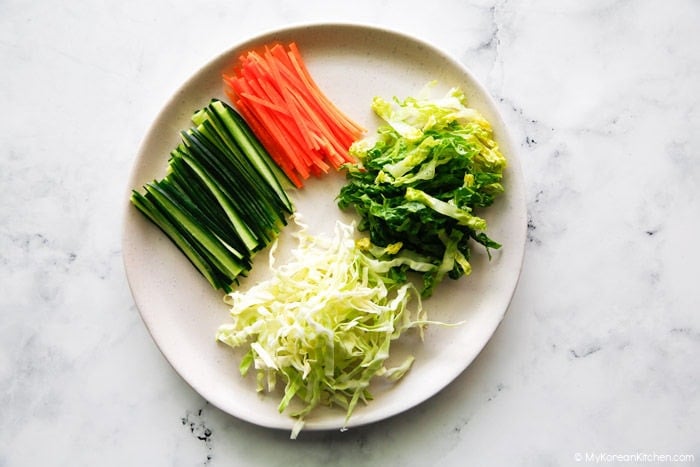 Thinly sliced vegetables placed on a large plate.