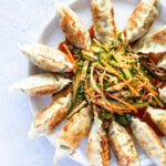 Pan-fried dumplings arranged around a seasoned salad on a large plate.