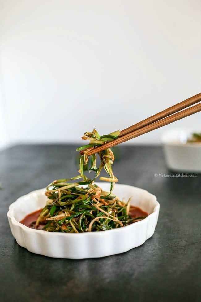 Holding green onion salad with wooden chopsticks.