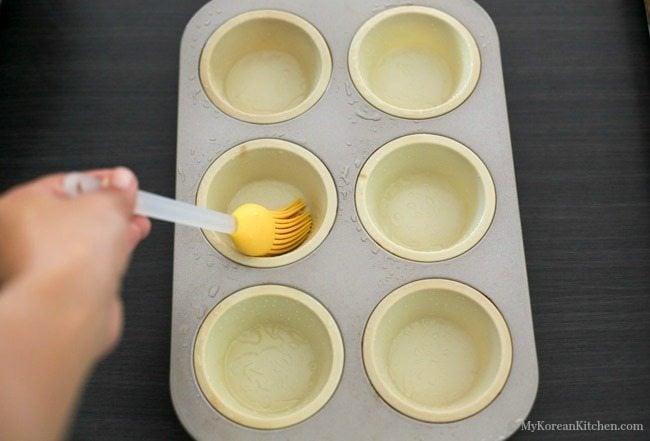 Basting oil in the muffin tray with yellow silicone brush