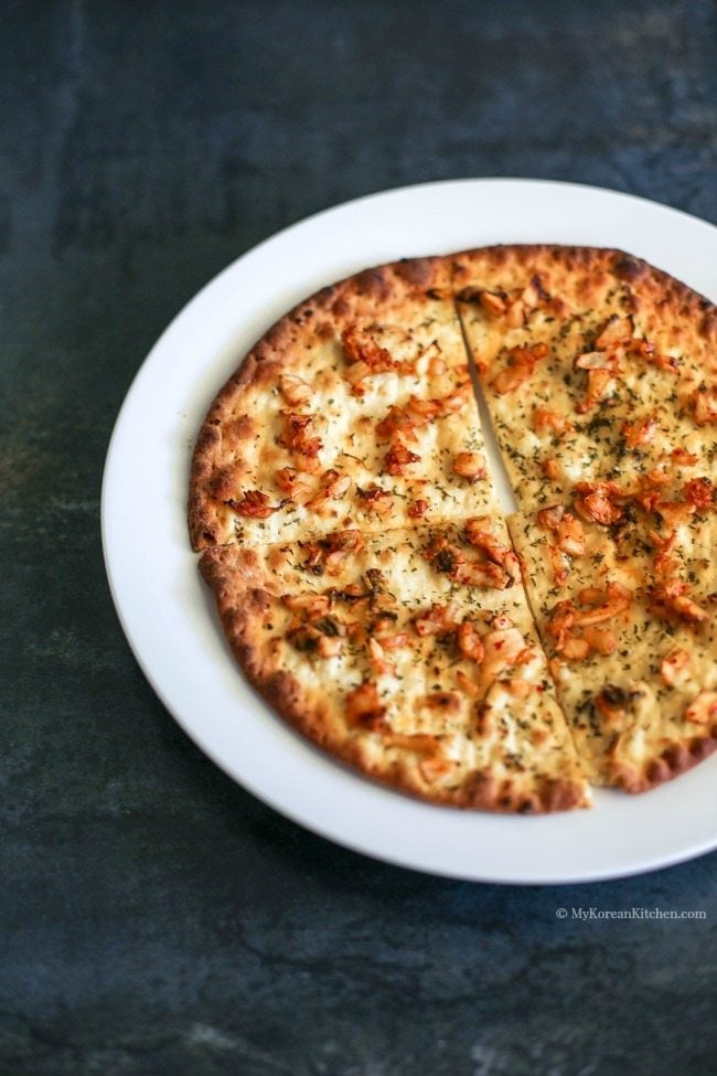 Kimchi pizza served on a white plate.