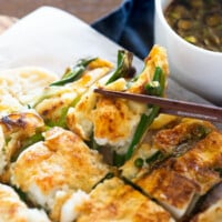 holding a pajeon piece with a pair of chopsticks