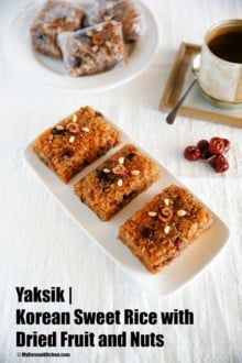 Yaksik dessert elegantly served on a rectangular white plate, with an additional three individually wrapped pieces arranged in the background on a matching round plate.