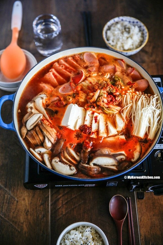 Korean army stew (Budae Jjigae) is a Korean fusion hot pot dish loaded with Kimchi, spam, sausages, mushrooms, instant ramen noodles and cheese. The soup is so comforting and addictive! | MyKoreanKitchen.com