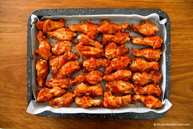 Marinated Korean chicken wings lined up on baking tray