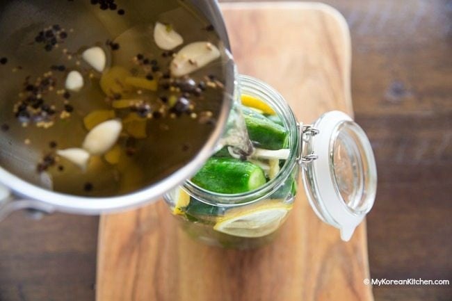 Pouring pickle brine over cucumbers