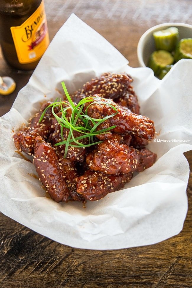 Korean fried chicken in a bowl, garnished with green onions and sesame seeds.