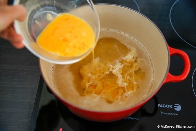 Dropping egg mixture into the broth