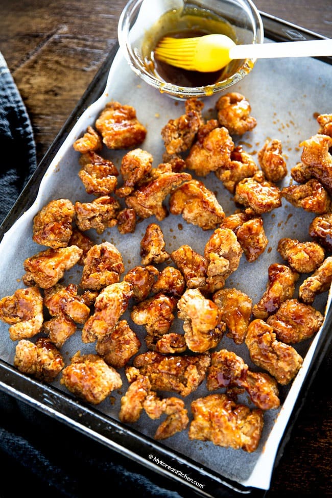 Basting soy garlic sauce on popcorn chicken with a brush