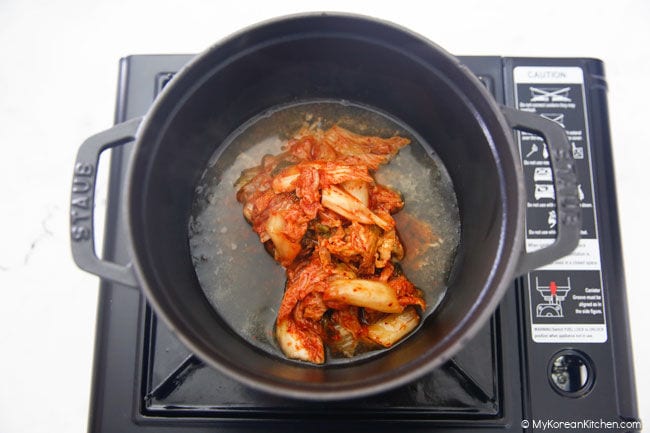 Kimchi and water from canned tuna in a black pot