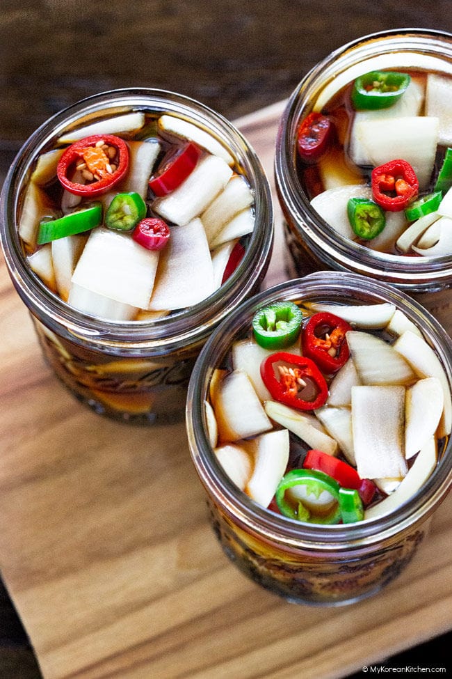 Three open jars filled with chopped onions, sliced chili peppers, and brine.