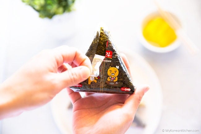 Pulling down the plastic tab of a triangle kimbap.