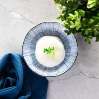 Pickled white radish served on a blue plate. Decorated with green sprouts.