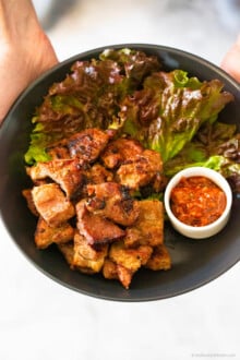 Korean BBQ Pork, lettuce, spicy dipping sauce in a black bowl.