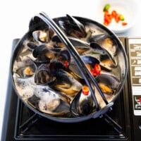 Boiling mussel soup in a black pot.