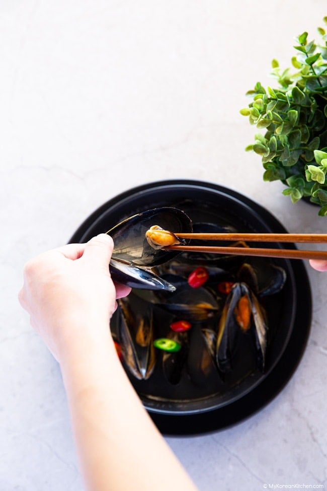 Picking out a mussel from the shell with chopsticks.