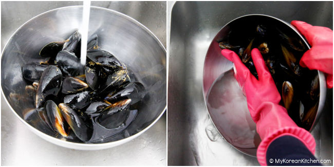 Washing mussels in a stainless steel bowl over running water.