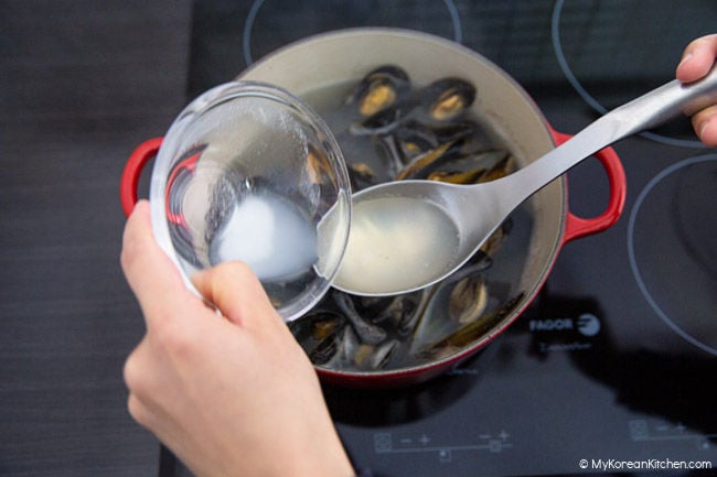 Pouring the sauce over the mussel soup to season it.