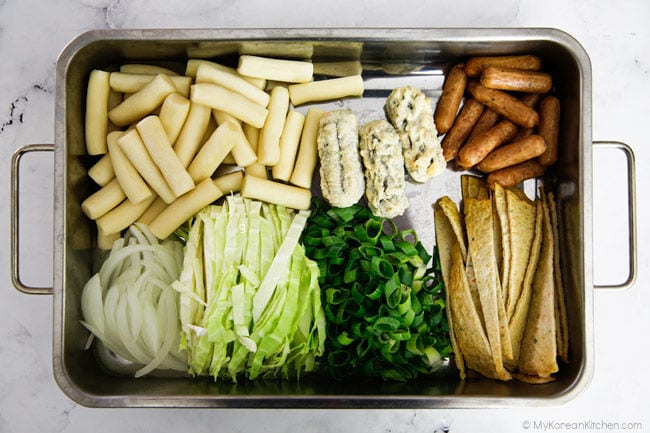 A display of rose tteokbokki ingredients in a stainless steel tray.