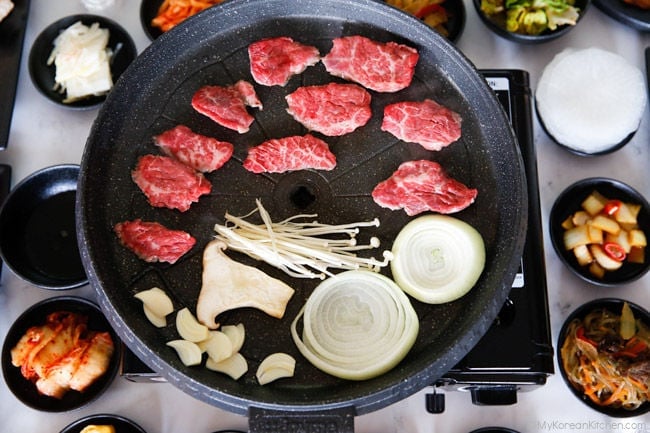 Grilling galbisal (boneless short ribs) with vegetables in a grill pan.