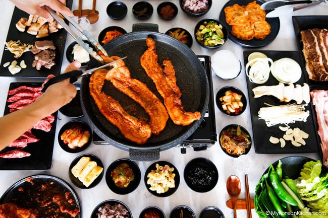 Cutting grilled, spicy pork belly with scissors.