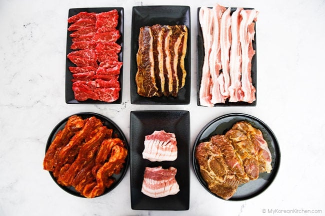 Multiple plates of Korean BBQ meat are available to grill.