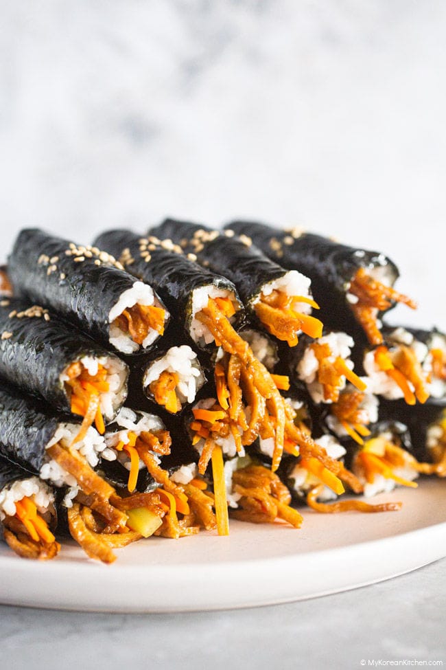 Displaying colorful piles of bite-sized mini kimbap on a white plate.