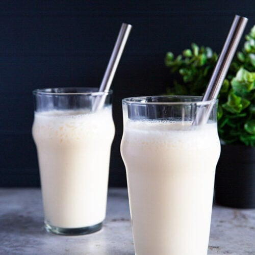 Two glasses filled with a blended makgeolli shake, served with sleek stainless steel straws.