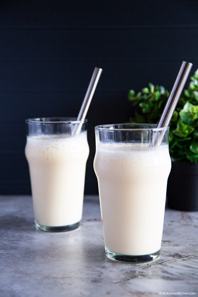 Two glasses filled with a blended makgeolli shake, served with sleek stainless steel straws.