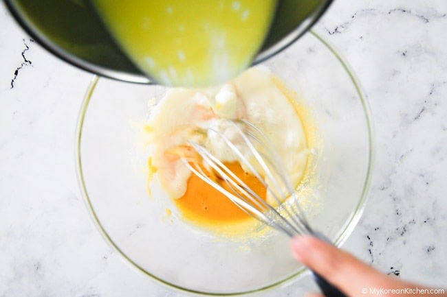 Combining warmed-up milk with egg yolk mixture.
