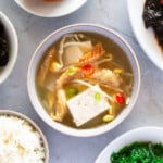Close up photo of dried pollack soup served with various Korean side dishes and rice.