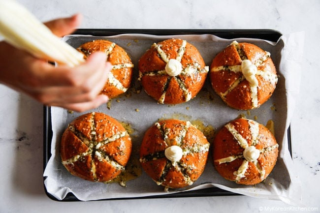Piping cream cheese into the middle of bread buns.