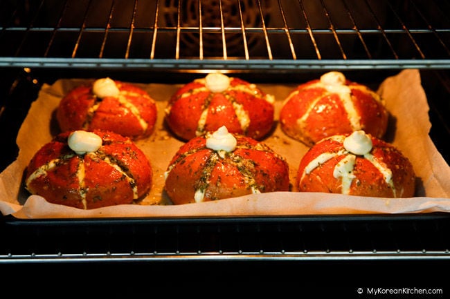 Six cream cheese garlic bread pieces being baked in an oven.