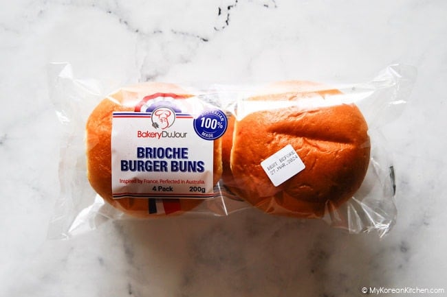 Brioche buns in a clear package on a marble bench.
