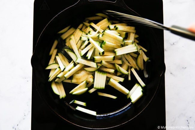 Zucchini added to the skillet for stir-frying.
