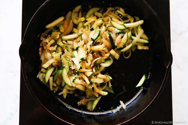 Sautéed zucchini and onions in a skillet.