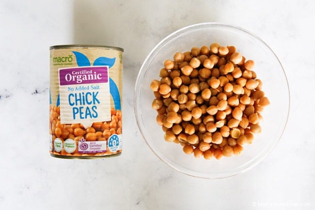 Can of chickpeas and chickpeas in a clear glass bowl.