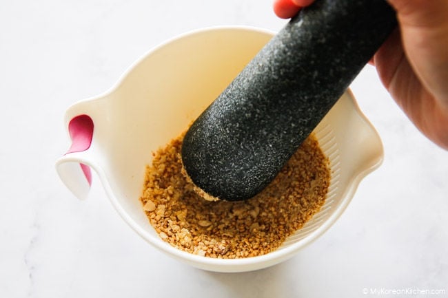 Grinding nut mixture with a pestle in a mortar.