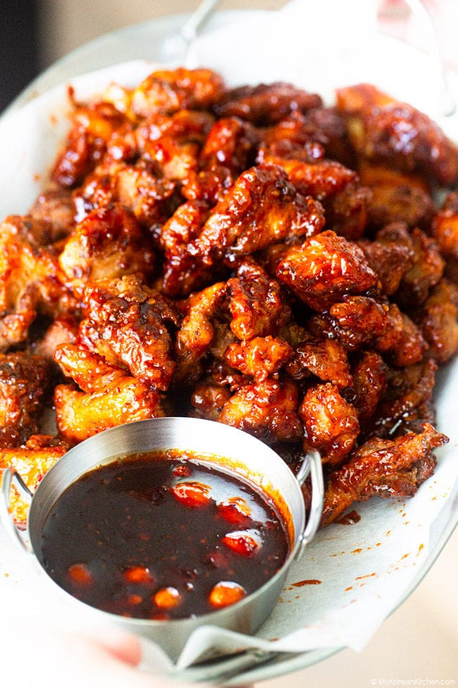 A pile of Korean-style mala chicken on a plate with a bowl of mala sauce.