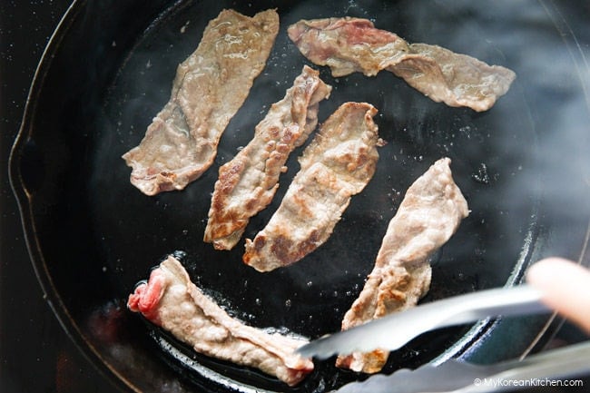 Chadolbaegi being grilled in a cast iron skillet.